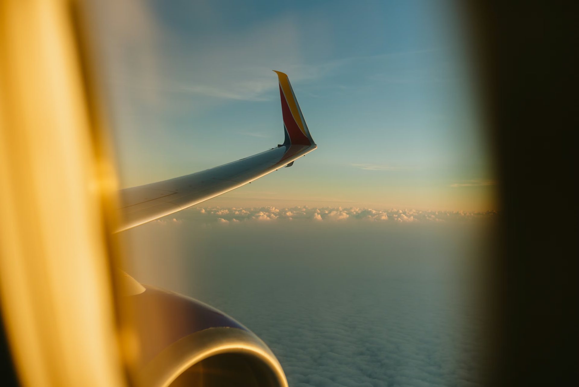 Airplane wing above clouds at golden hour